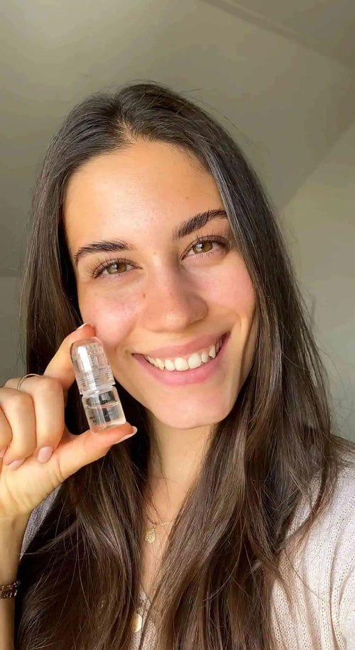 Woman holding a small bottle with a neutral background