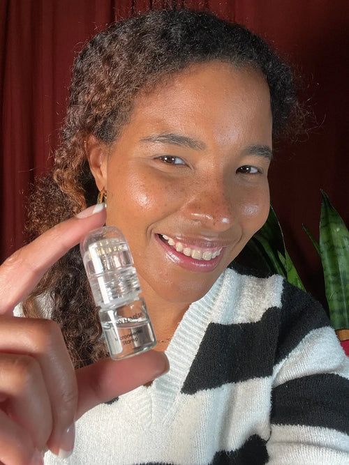 Woman holding a clear plastic object against a red curtain background