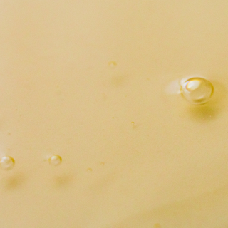 Close-up of a yellowish liquid with small bubbles on a beige background