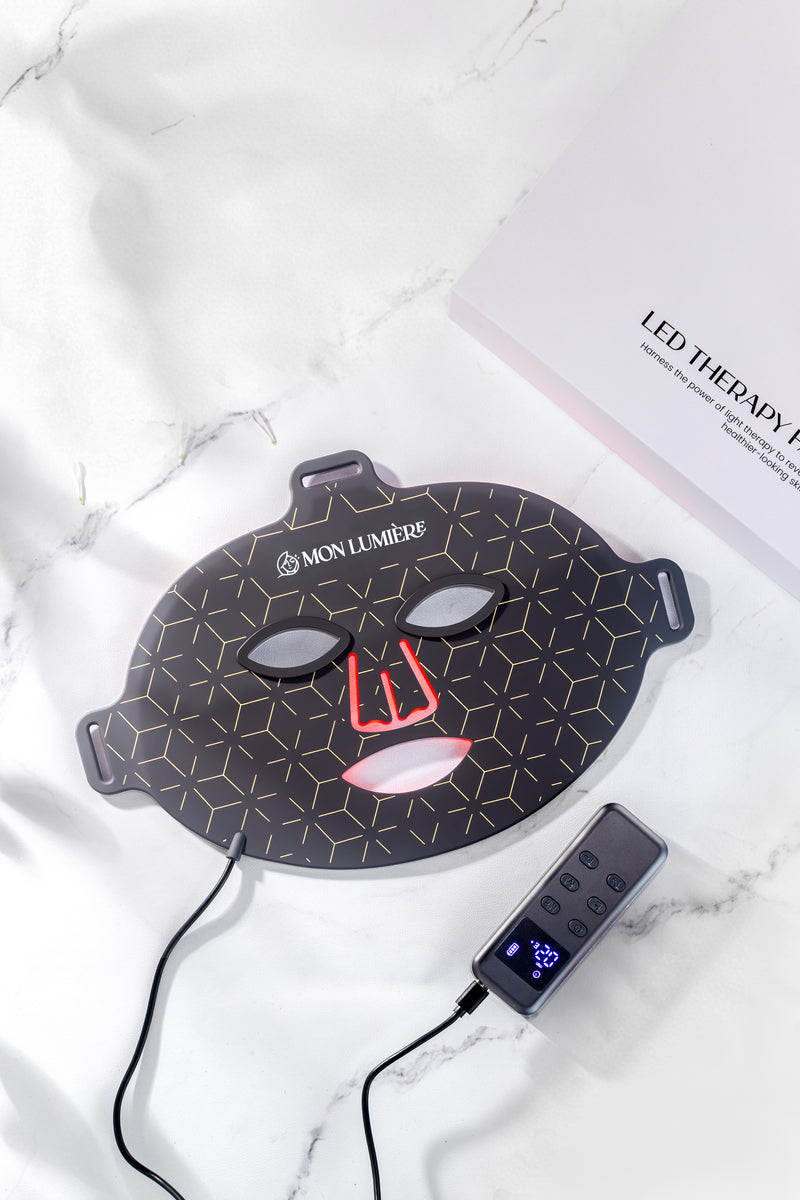 LED therapy face mask with power adapter on a white marble surface