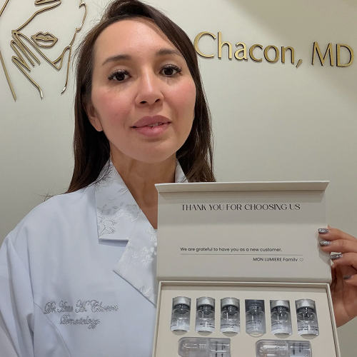 Woman in a white coat holding a box of skincare products with 'Chacon, MD' in the background.