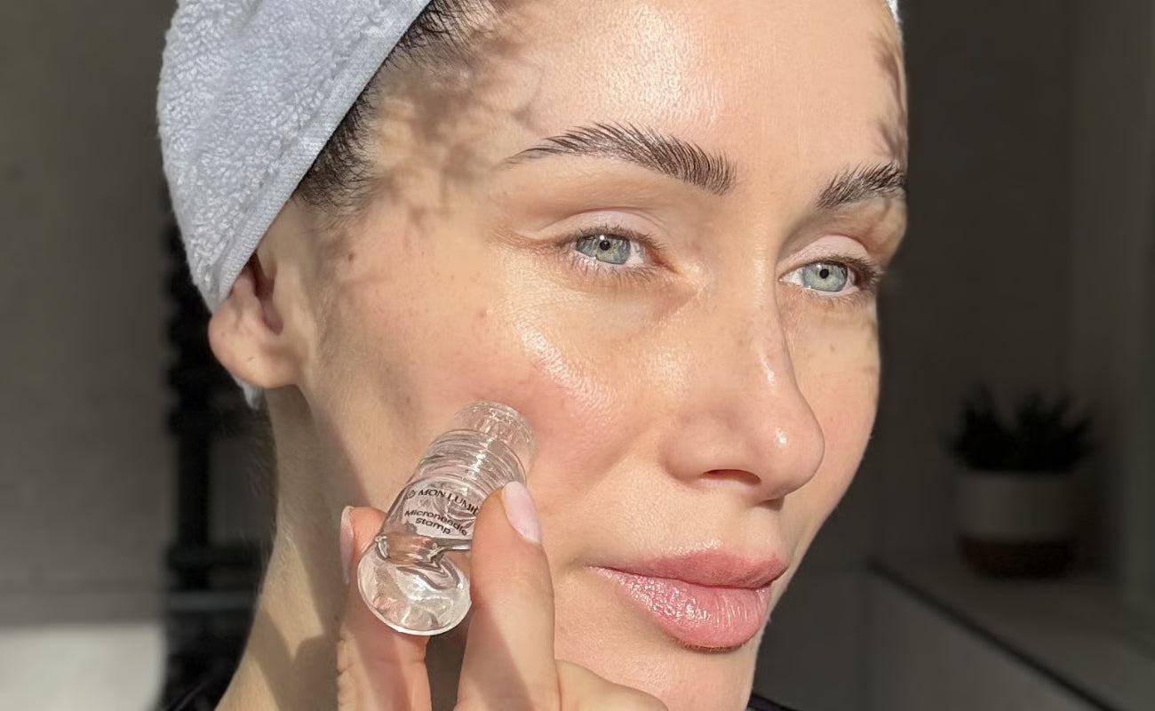 Woman applying skincare product with a towel on her head in a kitchen setting